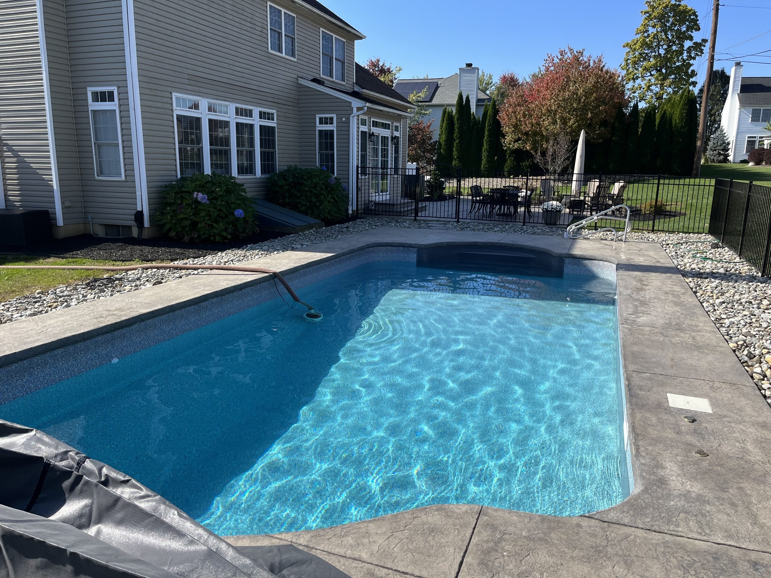 Rectangular fiberglass swimming pool with clean, sparkling water following routine pool maintenance.