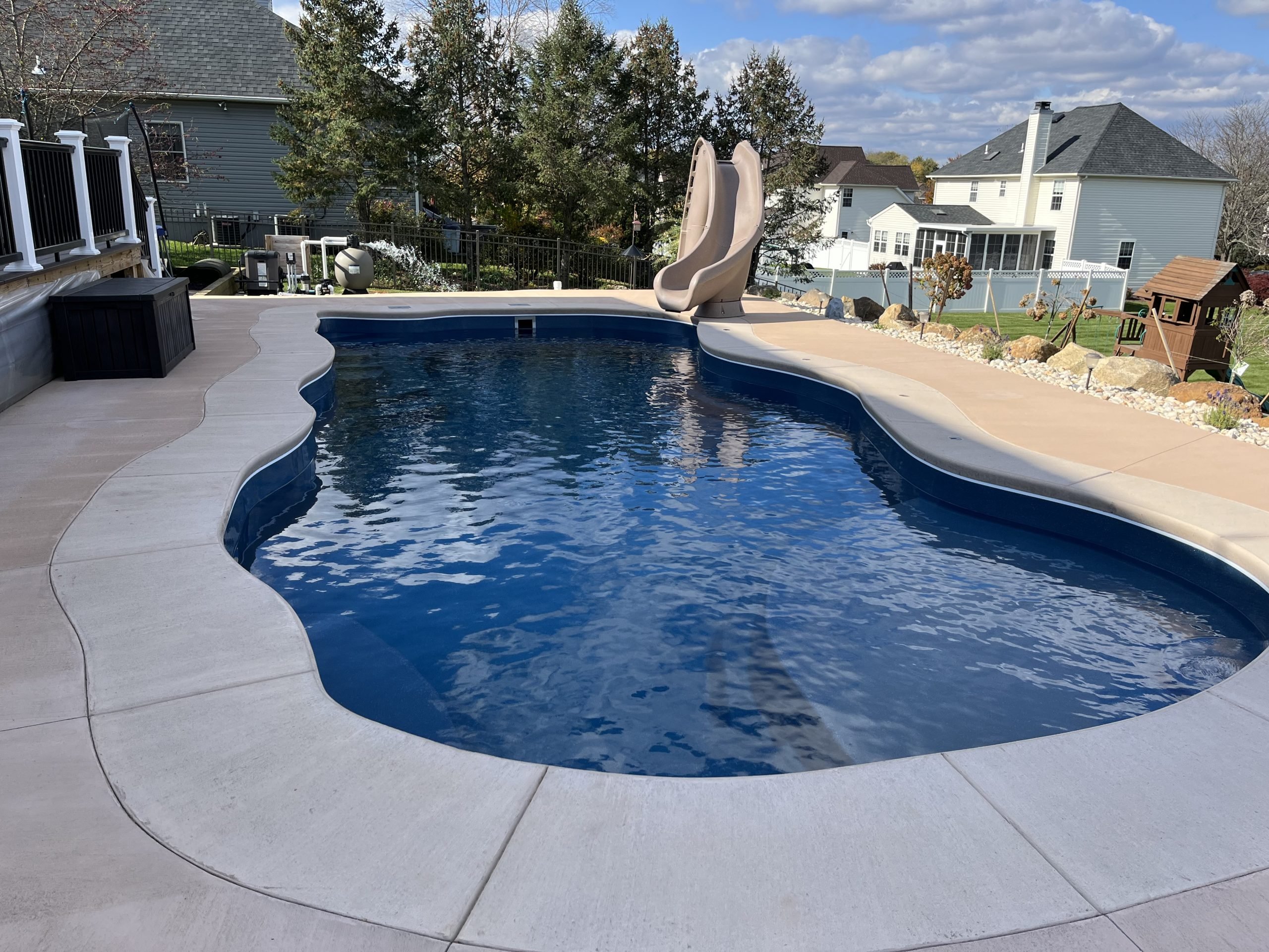 Backyard freeform swimming pool with a pool slide and clear, balanced water maintained by pool professionals.
