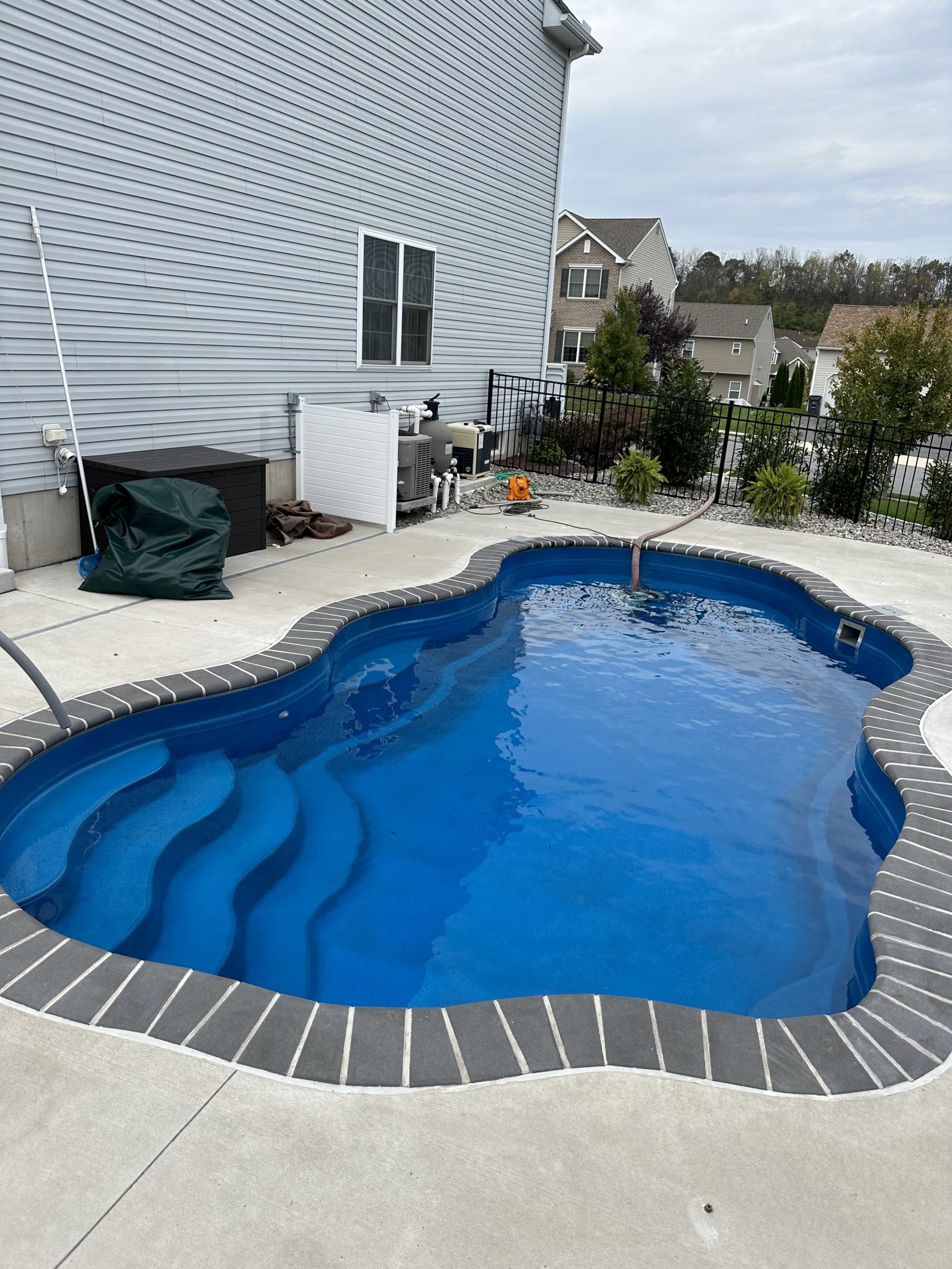 Freeform fiberglass swimming pool after a professional pool opening, featuring clean water and freshly serviced equipment.