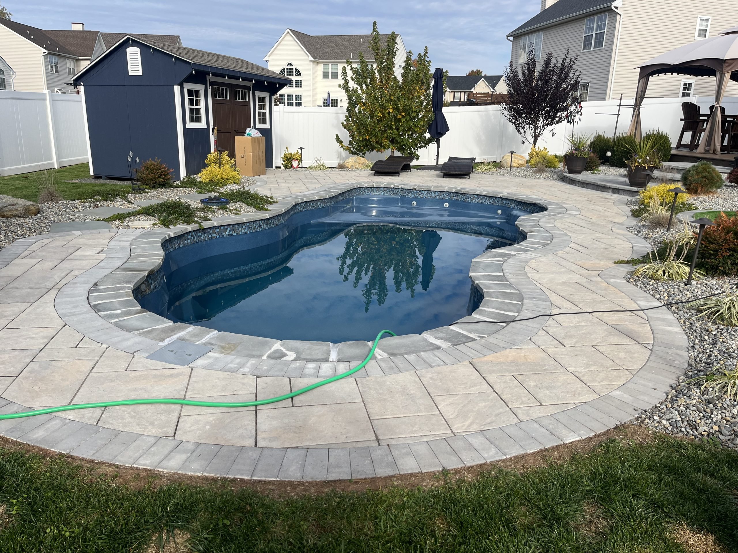 Residential freeform swimming pool with a decorative stamped concrete patio and professionally maintained water.
