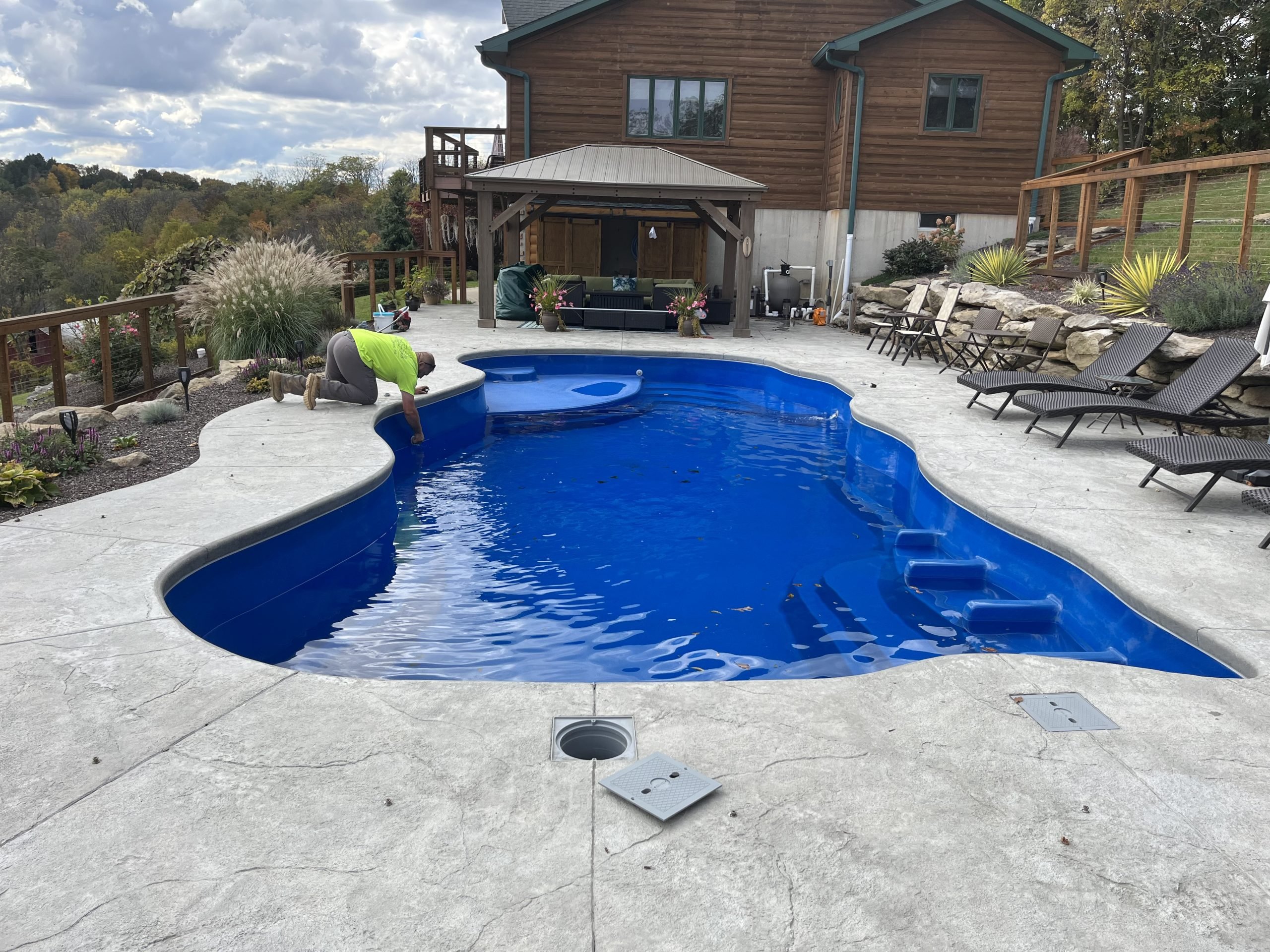 Freeform residential swimming pool after a professional pool opening, showcasing clear blue water and a clean pool deck.