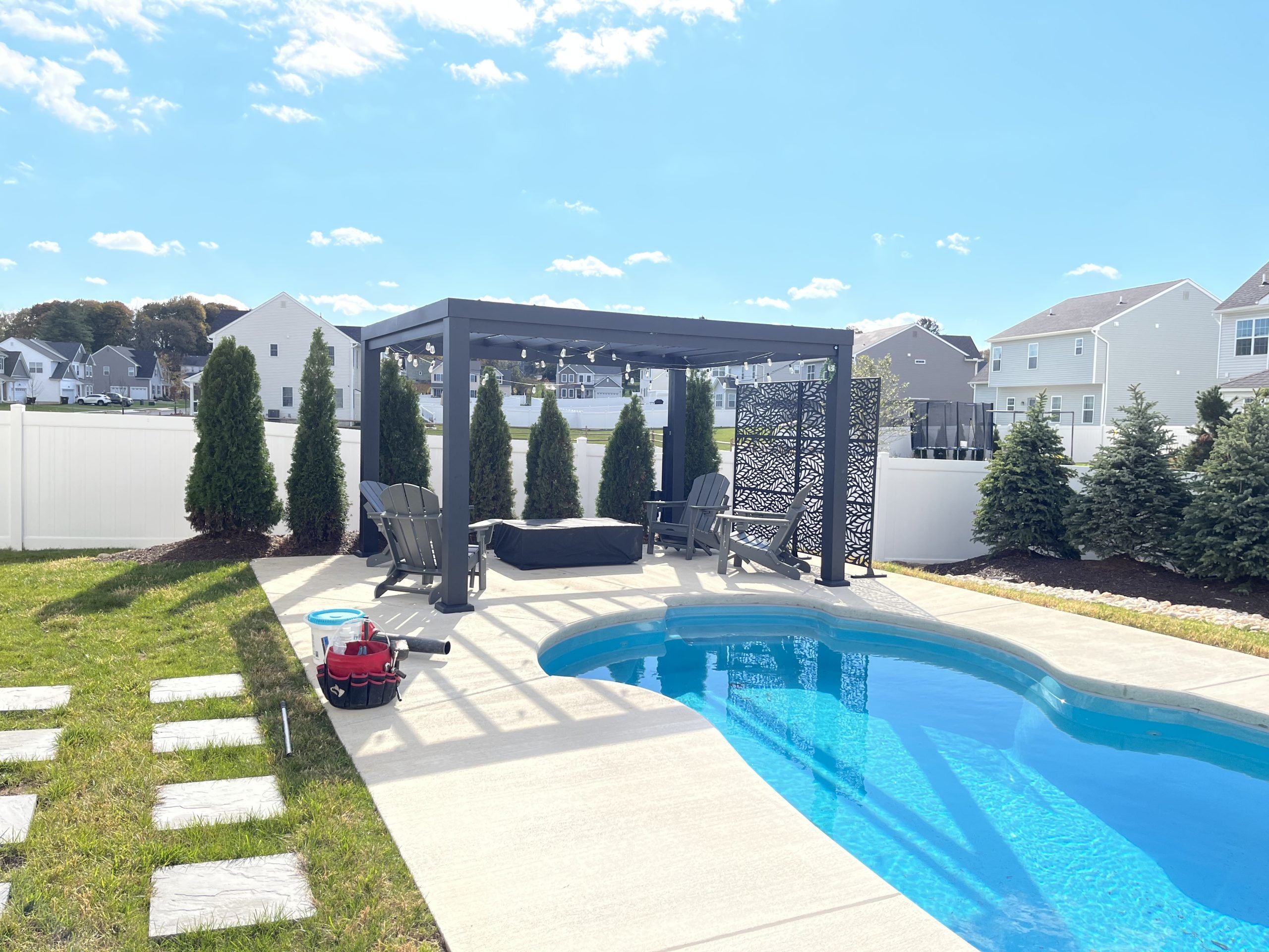 Modern backyard swimming pool professionally opened for the season with sparkling water, pergola, and landscaped patio.