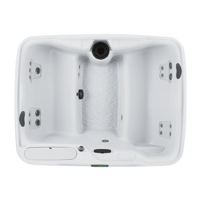 Direct top-down view of the white Fantasy Spas Enamor Premier hot tub interior, highlighting facing bench seating, synthetic wood pillow accents, textured footwell, and molded ice bucket.